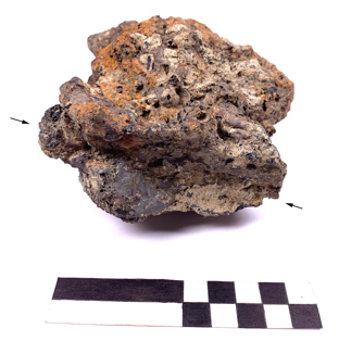 Illlus. 5: Smithing hearth cake from Clenor South 2, with imprint of iron tuyere (arrowed) (Photo: Paul Rondelez).